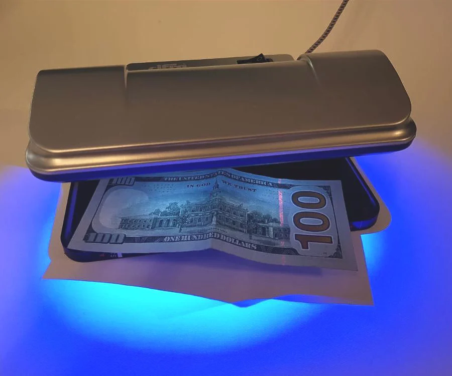 Detector UV Cifra XB-115 verificando un billete de 100 dólares — sirve para distintas monedas